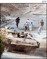 Children run away from an armoured vehicle in Jenin