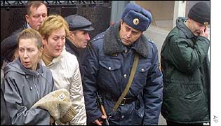 Armed Russian policeman outside Moscow hospital with anxious relatives