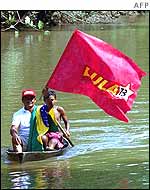 Two men wave Lula flag while in a boat in the northern Brazilian state of Para