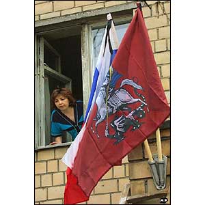 A woman looks out of the window in front of the theatre where the hostage crisis took place Russia's national flag, left, and Moscow's municipal flag don ribbons