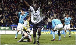 Michael Ricketts celebrates Bolton's good fortune as Phil Babb crouches over in despair