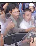 The cleric's supporters surround a vehicle as he is taken away 