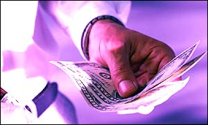 A hand holding out a bundle of notes