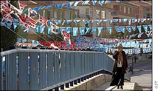 A woman walks in a street decorated with pre-election flags in the village of Kecioren near Ankara 