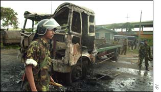 A Sri Lankan soldier walks past a burnt lorry after the rioting