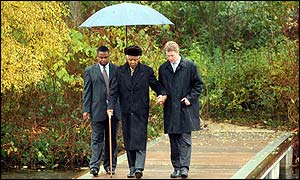 Nelson Mandela (centre), Earl Spencer (right) and an aide walk on bridge to island where Princess Diana is buried