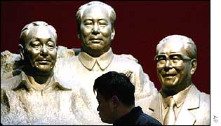A Chinese man is silhouetted against busts of Chinese Communist leaders Deng Xiaoping, left, Mao Zedong, centre, and Jiang Zemin