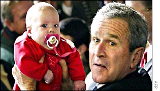 George W Bush holds a baby at a rally