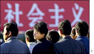 Visitors stand near a banner which says Socialism, near the Great Hall of the People, the venue of the 16th Chinese Communist Party Congress