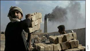 An Iraqi labourer carries bricks at a factory in Khankin 