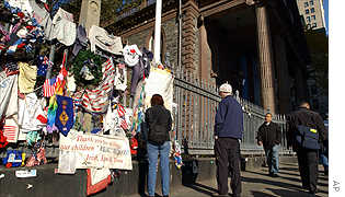 Passersby view what is still remaining on the fence of St Paul's Chapel in New York