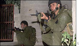 Israeli soldiers aim at a house