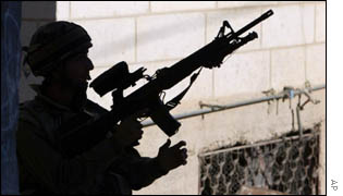 An Israeli soldier holds his machine gun during a search operation along the streets of the West Bank of Hebron 