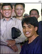 Bali bombing suspect Amrozi (right) poses for reporters with police