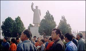 Tourists from neighbouring provinces gather around a tour guide at the foot of the Mao Zedong statue in Nanjie's main square