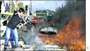 A Palestinian boy tosses a tire into a fire at a road-block near Bethlehem