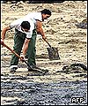 Spanish navy soldiers help to clear a beach of oil