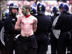 Police officers arrest a protester in Trafalgar Square