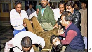 An injured Indian policeman is carried by rescuers