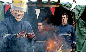 A striking firefighter wears a mask of Tony Blair