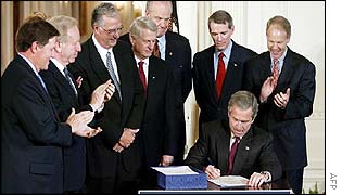 George W Bush signs the Homeland Security Bill as members of Congress applaud