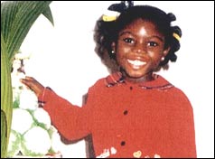 Anna posing for a photo beside a plant 
