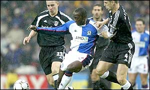 Dwight Yorke fends off challenges from Andy Melville (left) and Sean Davis