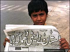 A young newspaper vendor holds up the evening paper - 28 May 1998