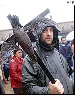 A protester marches with a crucified bird covered in oil