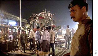 A policeman stands guard while the bomb squad inspect the site of the bus bomb