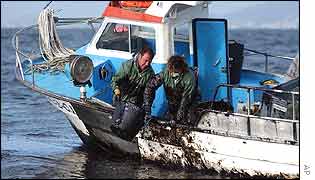 Fishermen off the north-western Spanish coast collect oil from the sea 