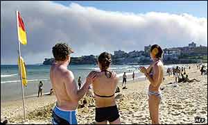 Beach-goers watch the plumes of smoke