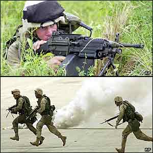 A marine aims with a machine gun, more run past smoke