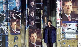 Man stands among posters of Vojislav Kostunica and Vojislav Seselj
