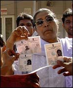 Angry voters in Juhapura wave their identity cards, alleging their names were missing from the voter list