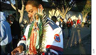 A man carries a statue of the Virgin of Guadalupe