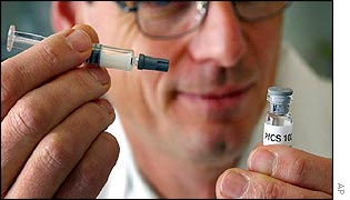 A Swiss scientist holds a flask and syringe containing a test vaccine against the malaria