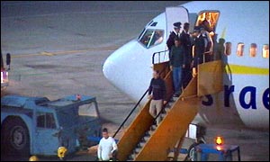 Police lead people off the plane