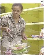 A customer selects an item from an almost bare shelves at a supermarket in Caracas