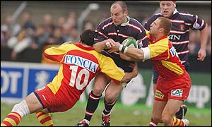 Gloucester's fly-half Ludovic Mercier is tackled by two Perpignan players