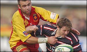 Gloucester's scrum-half Andy Gomarsall struggles to get his pass away 