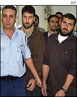 Two of the men are escorted by an Israeli policeman