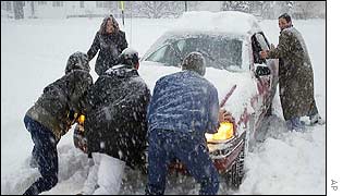 People push a car out of a driveway in Oneonta, New York