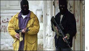 Two armed Palestinians walk along a street near the scene of a gun battle with Israeli soldiers, in the West Bank town of Nablus
