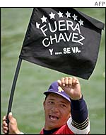 A protestor waves a flag with an anti-Chavez slogan