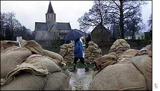 Walkers pass a pile of sandbags at the village of Afsnee