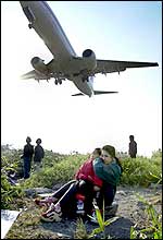 Taiwanese mother holds her son's ears as they watch a plane landing at Taipei domestic airport