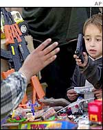 Children haggle with a street trader over toy gun prices