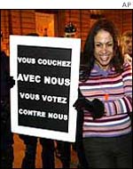 A prostitutes holds banner outside parliament in Paris as riot police look on