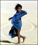 A Tuareg girl walks in the mid-day heat, in the remote oasis of Bou Djebeha, in the Sahara Desert 